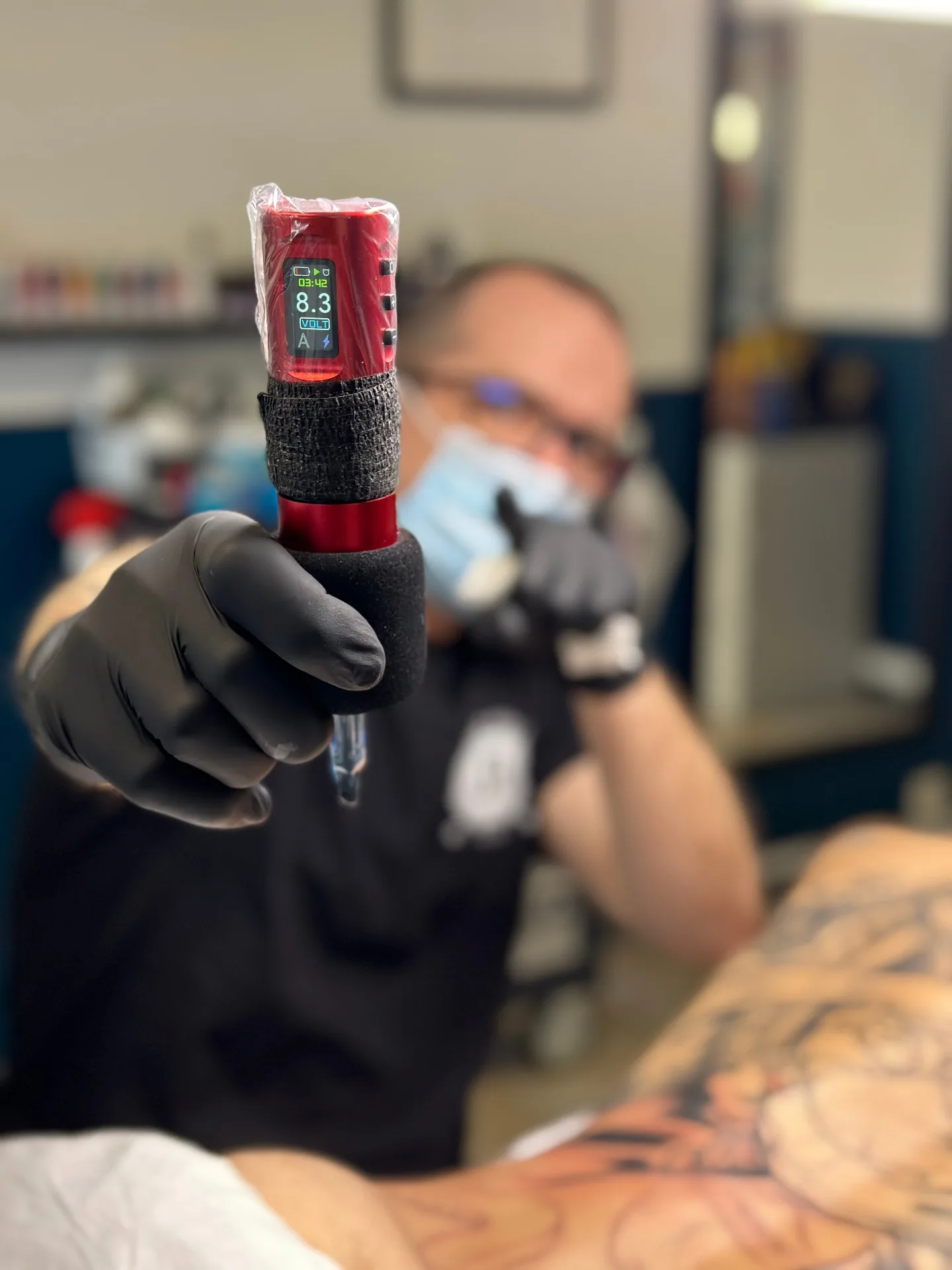 Tatoueur professionnel présentant sa machine de tatouage en formation EvoTattoo